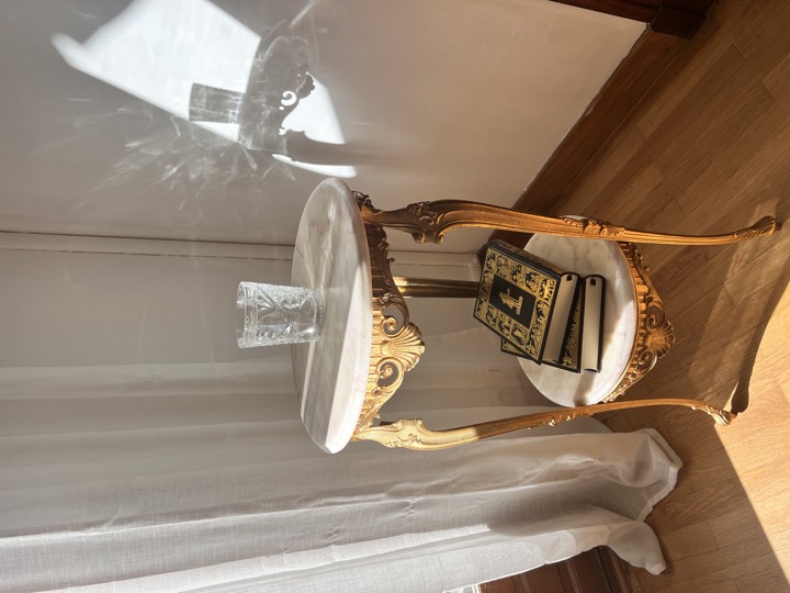 Gilt two-tier side table with a marble top, cut-glass tumbler and books